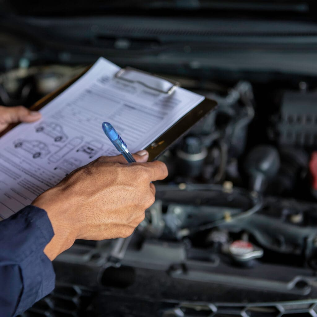 A mechanic service car in garage is check a list cars.